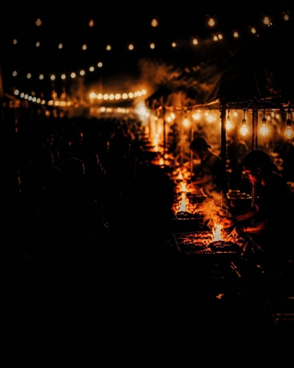 A festival vendor row at night under string lights
